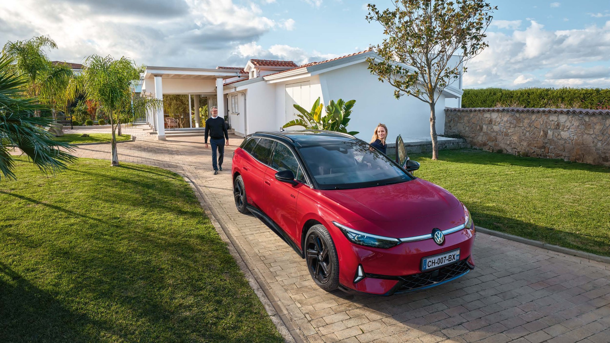 Volkswagen ID.7 Tourer rouge près d’une maison
